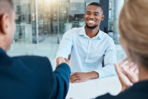 Shaking hands, interview and business people give a handshake after hiring a new company employee.