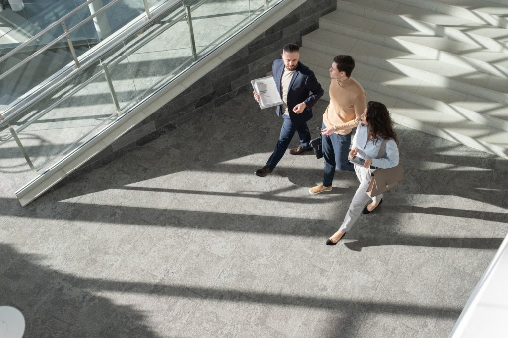 Above view of three young coworkers moving down lounge of office center